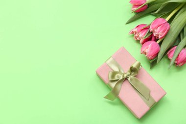 Yeşil arka planda hediye kutusu ve bir buket güzel lale. Uluslararası Kadınlar Günü