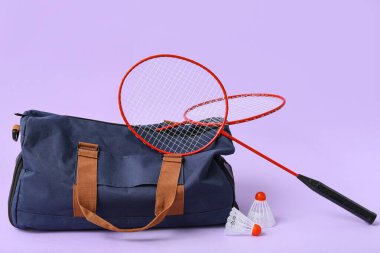 Mor arka planda spor çantası ve badminton raketleri