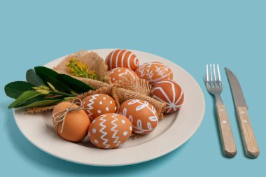 Paskalya yumurtaları ve mavi arka planda sarı çiçeklerle güzel bir masa.