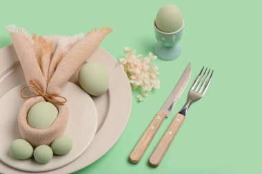 Yeşil arka planda Paskalya yumurtaları ve güzel çiçekleri olan masa ayarı