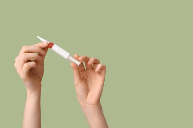 Yeşil arka planda deri altı kalemi olan kadın eller.