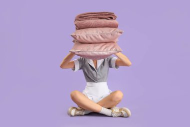 Leylak arka planında oturan yastıklı ve sıcak ekoseli kadın hizmetçi.