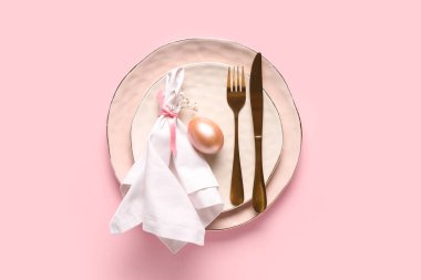 Paskalya yumurtası ve pembe arka planda çigila çiçekleri olan güzel bir masa.