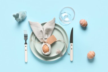 Mavi arka planda Paskalya yumurtası ve oyuncak tavşanı olan güzel bir masa.