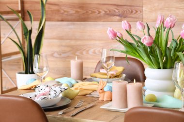 Güzel Paskalya sofrası, laleler, çatal bıçak takımı ve boyalı yumurtalarla dolu.