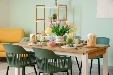 Paskalya sofrası, çiçekler ve sandalyelerle dolu şenlikli yemek odasının içi.