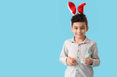 Mavi arka planda oyuncak tavşanı olan tavşan kulaklı şirin bir çocuk. Paskalya kutlaması