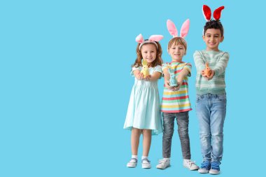 Mavi arka planda oyuncak tavşanı olan tavşan kulaklı şirin çocuklar. Paskalya kutlaması