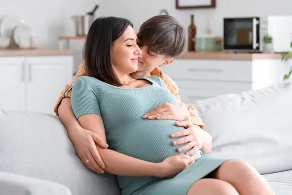 stock image Young pregnant couple hugging on sofa at home