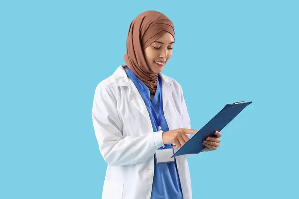 Female Muslim Doctor Clipboard Blue Background — Stock Photo, Image