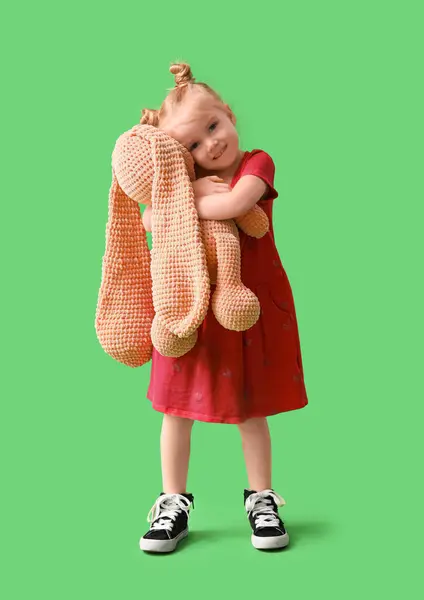 可爱的小女孩抱着绿色背景的小兔子 — 图库照片