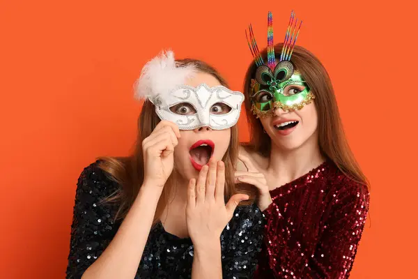 Шокированные Молодые Женщины Карнавальных Масках Оранжевом Фоне — стоковое фото