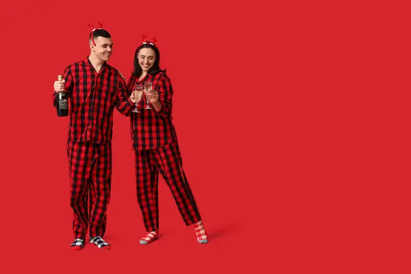 Jovem Casal Feliz Pijama Natal Com Champanhe Fundo Vermelho — Fotografia de Stock