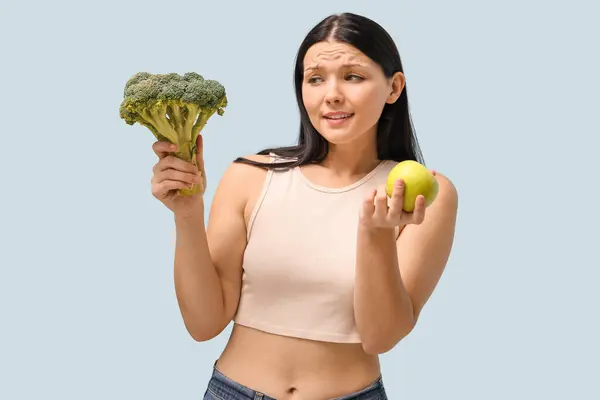 Schöne Junge Frau Mit Frischem Apfel Und Brokkoli Auf Blauem — Stockfoto