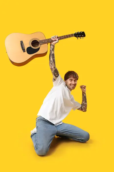 Młody Wytatuowany Mężczyzna Gitarą Tańczący Żółtym Tle — Zdjęcie stockowe