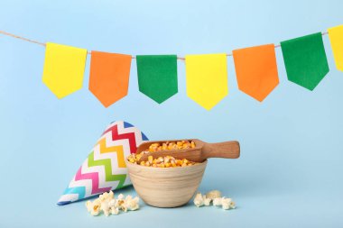 Bir top mısır, parti şapkası ve mavi arka planda bayraklarla dolu bir kase. Festa Junina (Haziran Festivali) kutlaması