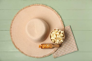 Yeşil ahşap arka planda bir kase patlamış mısır, hasır şapka ve peçete. Festa Junina (Haziran Festivali) kutlaması