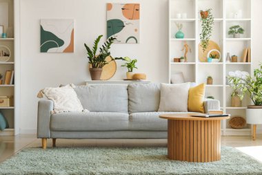 Kanepesi, masası ve çiçekleri olan bir oturma odası.