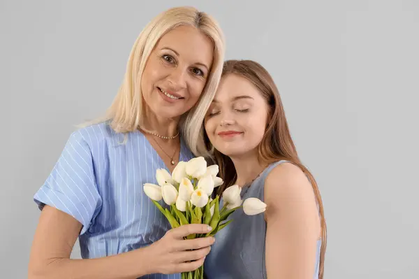 Giovane Donna Che Saluta Sua Madre Con Tulipani Sfondo Grigio — Foto Stock