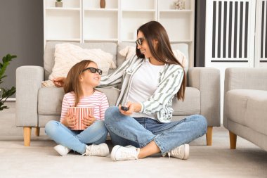 Mutlu anne ve 3 boyutlu sinema gözlüklü küçük kızı evde patlamış mısır izleyip film izliyorlar.