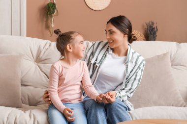 Mutlu anne ve küçük kızı oturma odasında kanepede oturuyor.