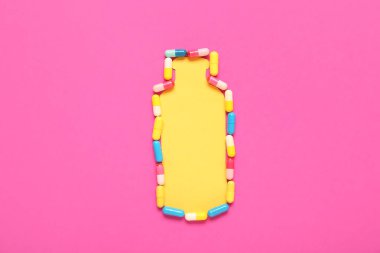 Pembe arka planda farklı haplardan yapılmış bir şişe.