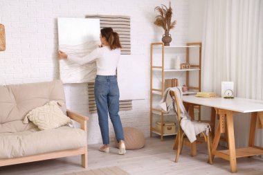 Beyaz tuğla duvara resim asan kadın oturma odasında, arka manzara