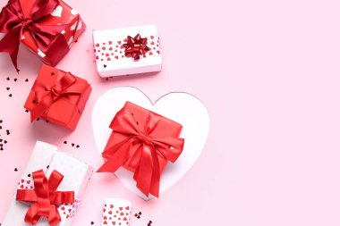 Konfetili hediye kutuları ve pembe arka planda kesilmiş kağıtlar. Sevgililer Günü kutlaması