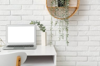 Bilgisayarlı modern çalışma alanı ve beyaz duvarın yanındaki ev bitkisi