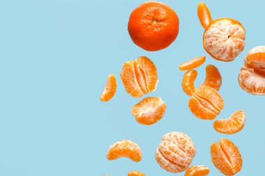 Mavi arka planda soyulmuş tatlı mandalinalar uçuyor