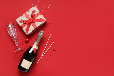 Kırmızı arka planda Sevgililer Günü kutlamaları için şampanya, cam ve hediye içeren kompozisyon