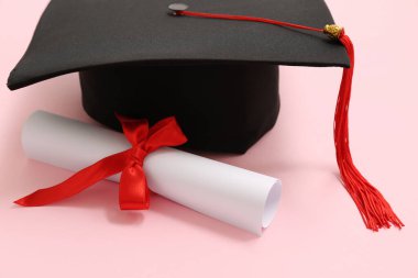 Mezuniyet şapkası ve pembe arka plan diploması.