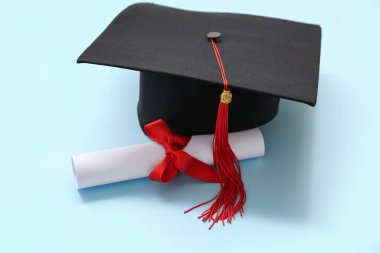 Mavi arka planda mezuniyet şapkası ve diploması.