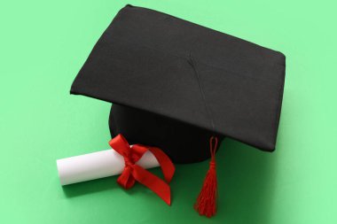 Mezuniyet şapkası ve yeşil arka plan diploması.