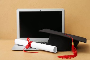 Diplomalı havan mermisi tahtası ve kahverengi arka planda modern laptop.