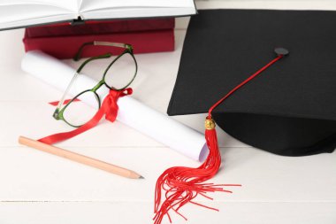 Havan mermisi, diploma, gözlük ve beyaz ahşap arka plan üzerine not defterleri.