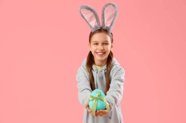 Paskalya tavşanı kulakları ve pembe arka planda yumurtası olan tatlı küçük bir kız.