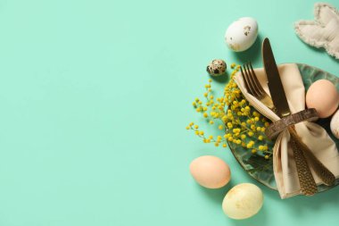 Paskalya yumurtaları ve turkuaz arka planda mimoza çiçekleri olan güzel bir masa.
