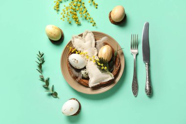 Paskalya yumurtaları, oyuncak tavşancık ve turkuaz arka planda mimoza çiçekleri olan güzel bir masa.