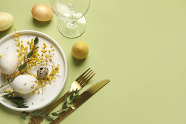 Yeşil arka planda Paskalya yumurtaları ve mimoza çiçekleri olan güzel bir masa.