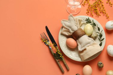 Paskalya yumurtaları, oyuncak tavşancık ve turuncu arka planda mimoza çiçekleri olan güzel bir masa.