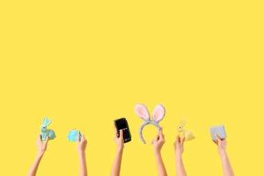 Paskalya dekoru olan kadınlar, cüzdanlar ve ödeme terminali sarı arka planda. İnternetten alışveriş