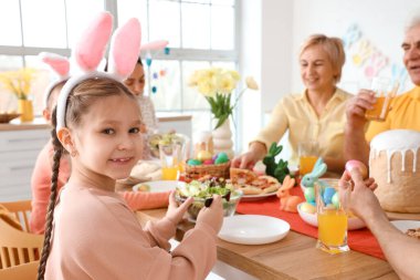 Küçük kız evde ailesiyle Paskalya yemeği yiyor.