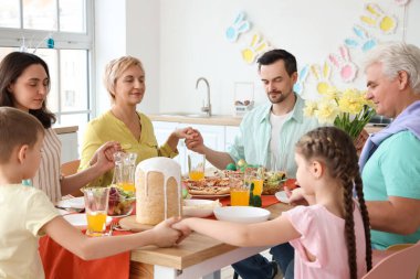Büyük bir aile mutfakta Paskalya yemeğinden önce dua ediyor.
