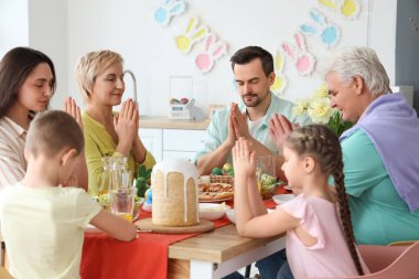 Büyük bir aile mutfakta Paskalya yemeğinden önce dua ediyor.