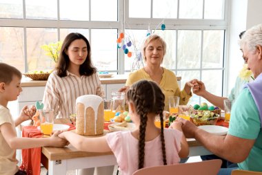 Büyük bir aile mutfakta Paskalya yemeğinden önce dua ediyor.