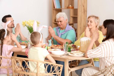 Paskalya yemeğinden önce evde dua eden mutlu bir aile