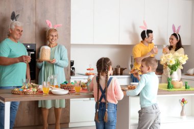 Mutlu bir aile mutfakta Paskalya yemeği yiyor.