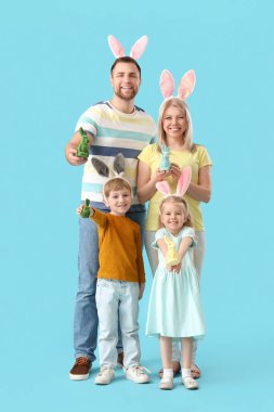Mavi arka planda Paskalya tavşanları olan tavşan kulaklı mutlu bir aile.