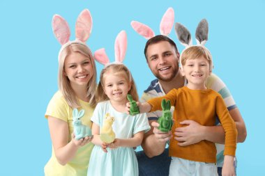 Mavi arka planda Paskalya tavşanları olan tavşan kulaklı mutlu bir aile.